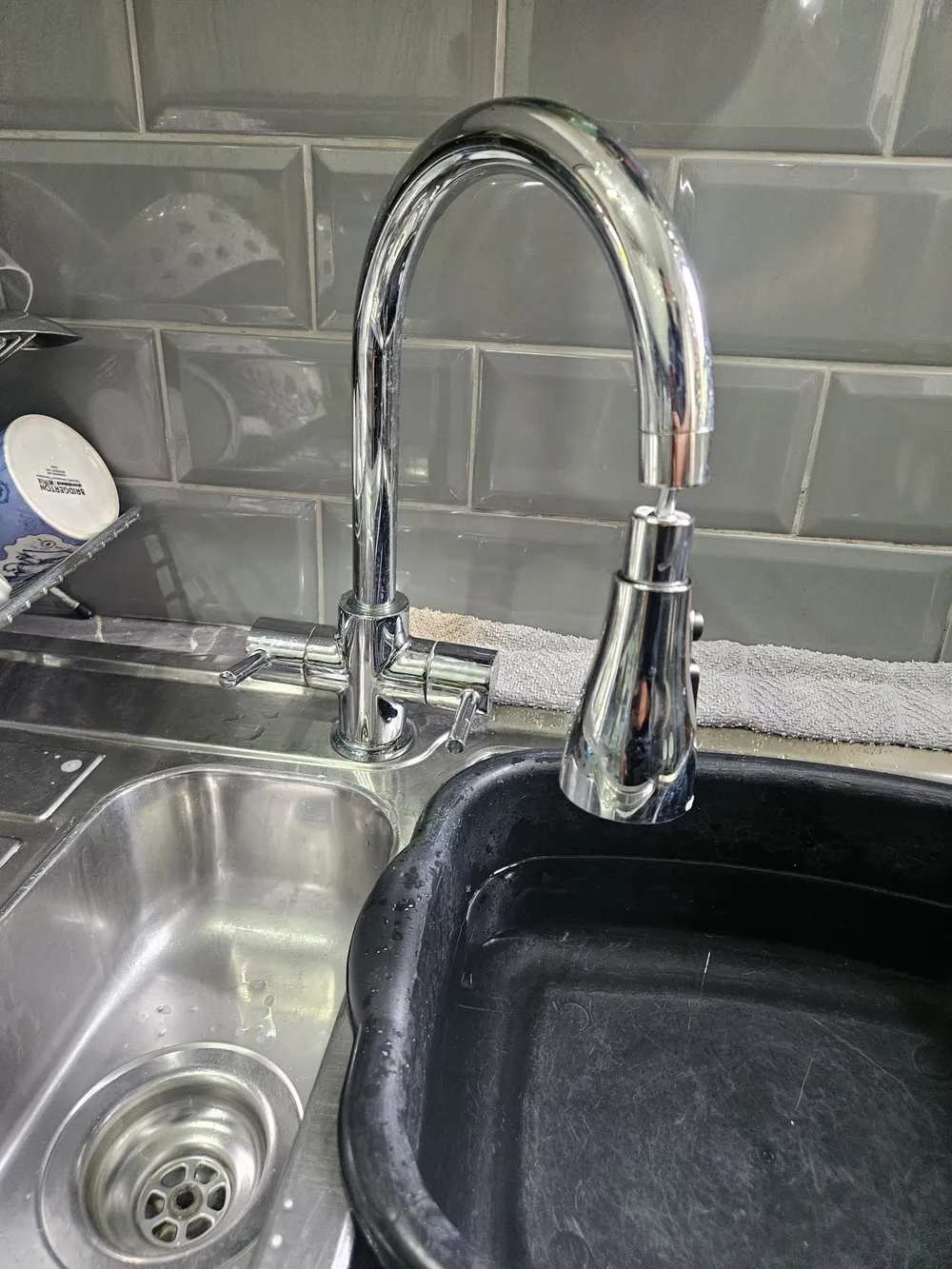 Pull-out spray kitchen mixer tap installed over a black composite sink